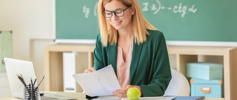 “teacher-at-desk-in-classroom“